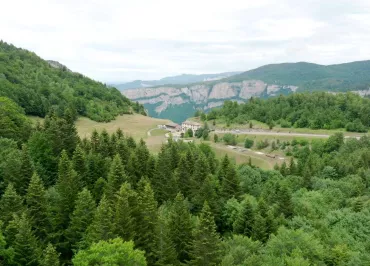 En contre plongée l’établissement se dévoile au loin entre les arbres et entouré de verdure avec en toile de fond les montagnes