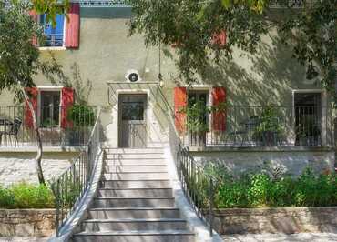 Vue de l'entrée de la maison avec une partie de la cour et du jardin