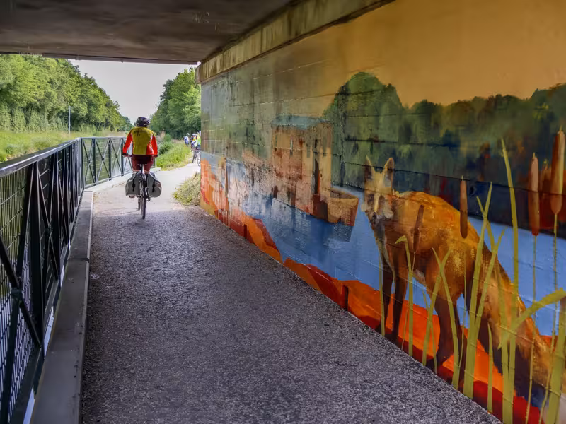 Fresque sous un pont avec un cyclotouriste qui passe devant
