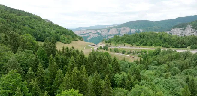 En contre plongée l’établissement se dévoile au loin entre les arbres et entouré de verdure avec en toile de fond les montagnes