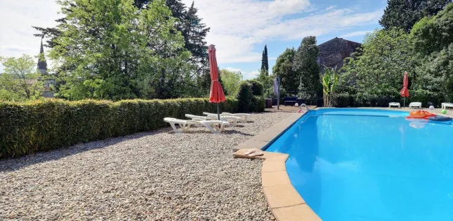 Grande piscine commune aux gîtes avec vue sur le clocher du village